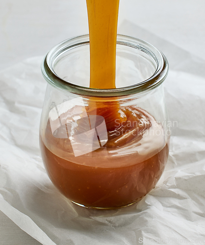 Image of freshly cooked homemade caramel sauce pouring in jar