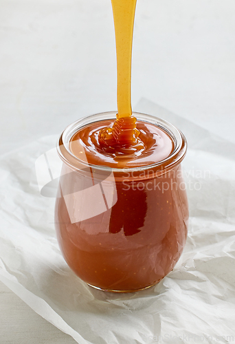 Image of freshly cooked homemade caramel sauce pouring in jar