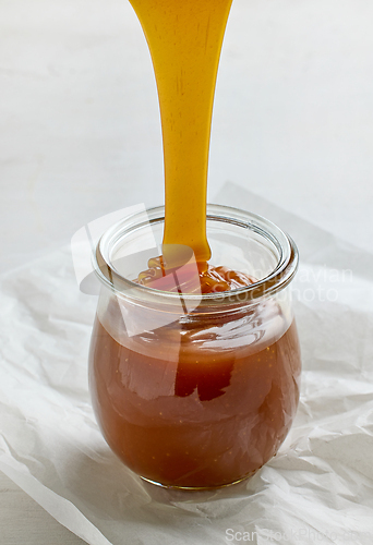 Image of freshly cooked homemade caramel sauce pouring in jar
