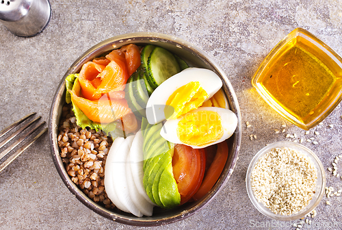 Image of Healthy vegan nutritious bowl with buckwheat. Salad of avocado, salmon, buckwheat, egg and tomato