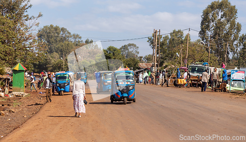 Image of Everyday scene capturing the flow of people and local taxi transport on a sunny day in Demebecha, Ethiopia