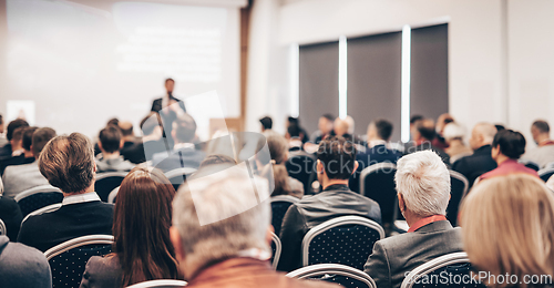 Image of Speaker giving a talk in conference hall at business event. Rear view of unrecognizable people in audience at the conference hall. Business and entrepreneurship concept.