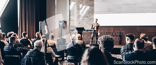 Image of Speaker giving a talk in conference hall at business event. Rear view of unrecognizable people in audience at the conference hall. Business and entrepreneurship concept.