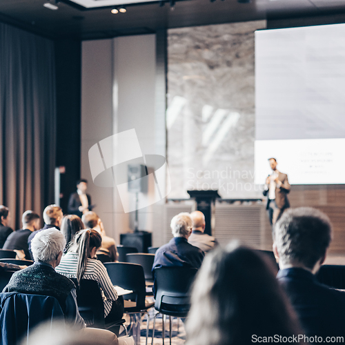 Image of Speaker giving a talk in conference hall at business event. Rear view of unrecognizable people in audience at the conference hall. Business and entrepreneurship concept.