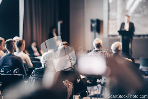 Image of Speaker giving a talk in conference hall at business event. Rear view of unrecognizable people in audience at the conference hall. Business and entrepreneurship concept.