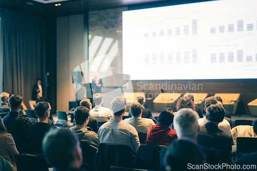 Image of Speaker giving a talk in conference hall at business event. Rear view of unrecognizable people in audience at the conference hall. Business and entrepreneurship concept.