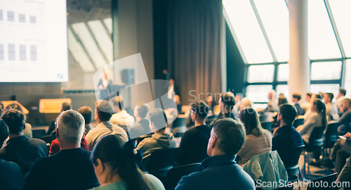 Image of Speaker giving a talk in conference hall at business event. Rear view of unrecognizable people in audience at the conference hall. Business and entrepreneurship concept.