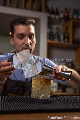 Image of Bartender pouring liquid into cocktail glass