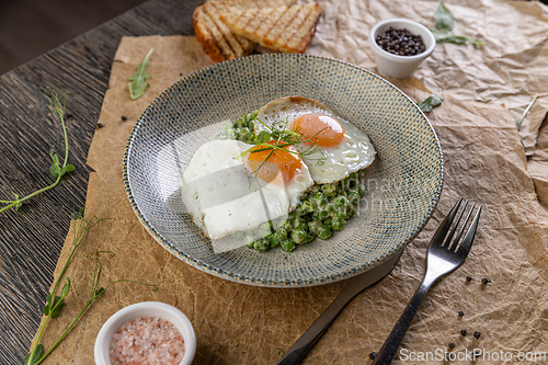 Image of Plate of fried eggs on green peas puree