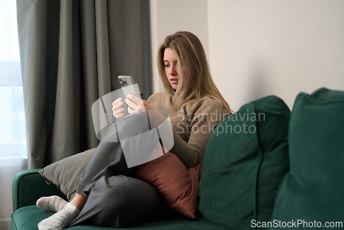 Image of Relaxed Moment on the Sofa with Phone and Coffee