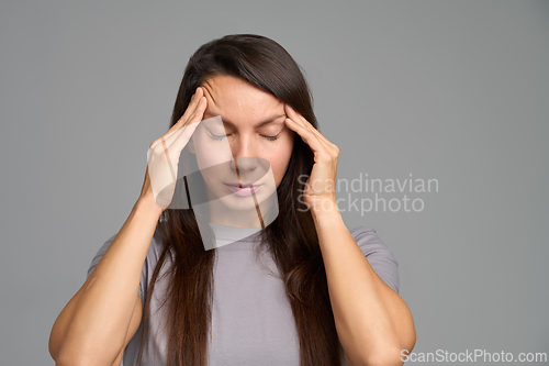 Image of Woman touching temples with calm closed eyes during early headache warning signs