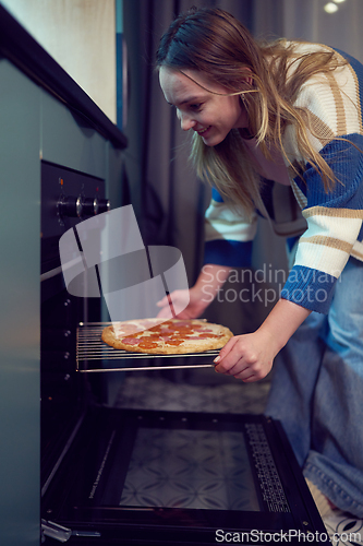 Image of Smiling woman baking pizza at home symbolizing comfort and slow life