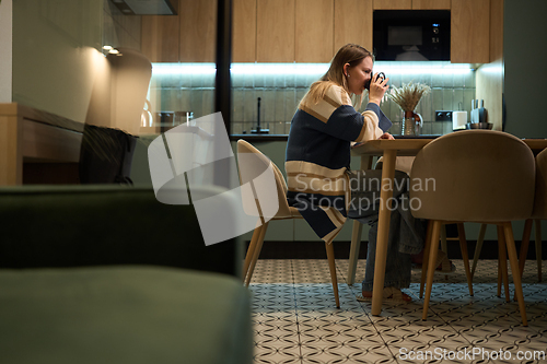 Image of Thoughtful woman with coffee mug resting at home in evening light