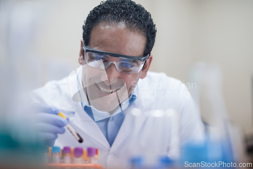 Image of Smiling medical technician in protective goggles analyzing a blood sample in a clinical laboratory
