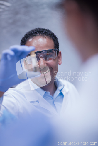 Image of Smiling lab technician holding a blood sample vial during medical testing in a clinical laboratory