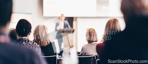 Image of Speaker giving a talk in conference hall at business event. Rear view of unrecognizable people in audience at the conference hall. Business and entrepreneurship concept.