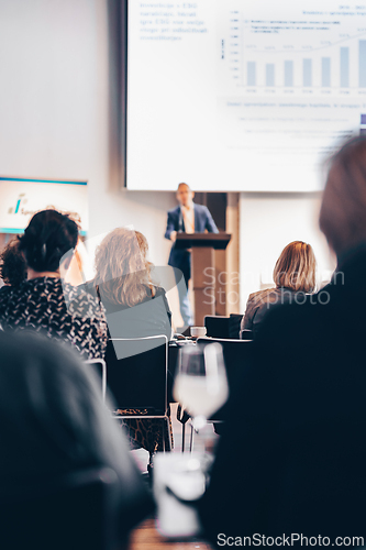 Image of Speaker giving a talk in conference hall at business event. Rear view of unrecognizable people in audience at the conference hall. Business and entrepreneurship concept.