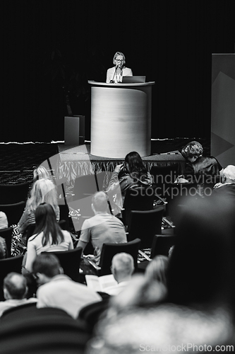 Image of Female speaker giving a talk on corporate business conference. Unrecognizable people in audience at conference hall. Business and Entrepreneurship event.