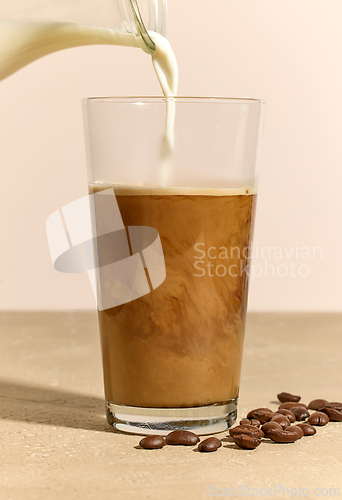 Image of milk pouring in glass of coffee