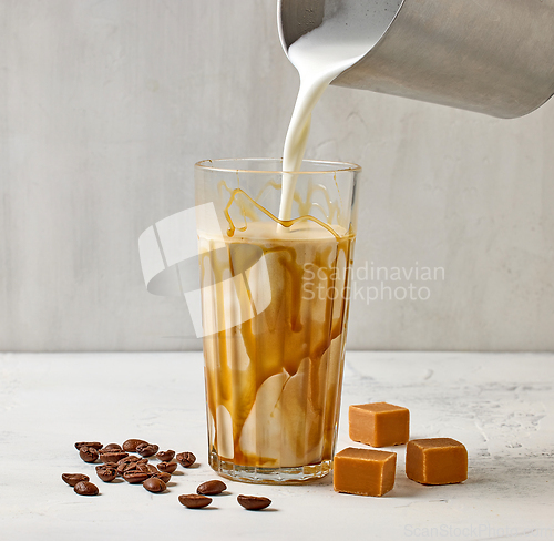 Image of closeup of caramel latte coffee glass on white table background