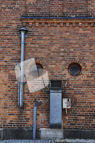 Image of brick wall of a factory with round windows and ventilation pipes