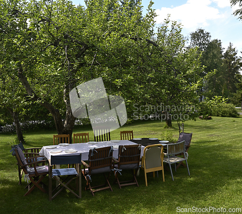 Image of table with tablecloth and chairs in the garden under an apple tr