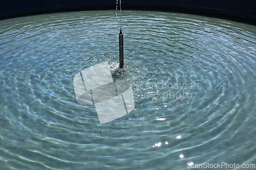Image of small fountain and radial waves on the water 