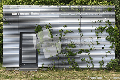 Image of A modern structure with a metal slatted facade partially covered