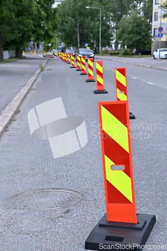 Image of A row of bright orange and yellow reflective traffic barriers