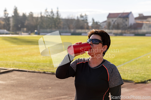 Image of Athlete woman drinking water