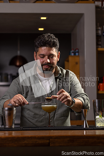 Image of Bartender garnishing a cocktail with passion fruit