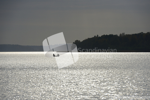 Image of a small boat with two people silhouetted against the shimmering 