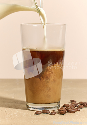 Image of milk pouring in glass of coffee