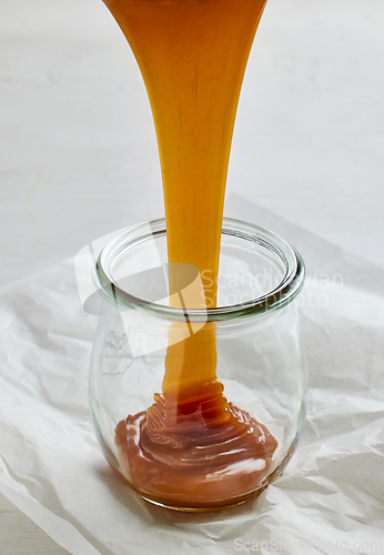 Image of freshly cooked homemade caramel sauce pouring in jar 