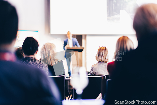 Image of Speaker giving a talk in conference hall at business event. Rear view of unrecognizable people in audience at the conference hall. Business and entrepreneurship concept.