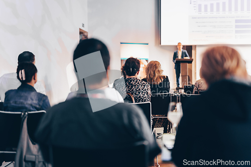 Image of Speaker giving a talk in conference hall at business event. Rear view of unrecognizable people in audience at the conference hall. Business and entrepreneurship concept.