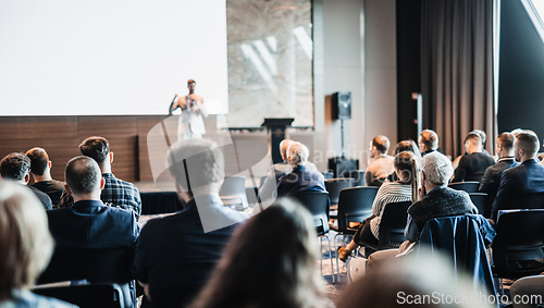 Image of Speaker giving a talk in conference hall at business event. Rear view of unrecognizable people in audience at the conference hall. Business and entrepreneurship concept.