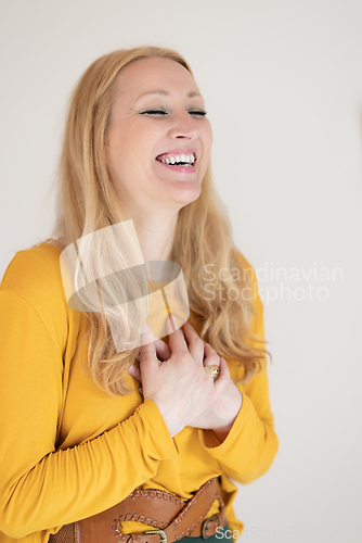 Image of Portrait of cheerful confident beautiful woman with long blond hair, wearing casual clothes, standing in relaxed pose with hands on chest, breathing deeply, doing breathing exercise