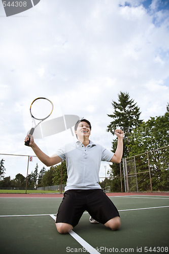 Image of Asian tennis player in joy after winning