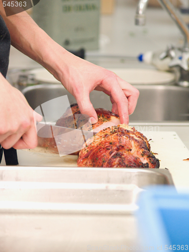 Image of Chef cutting roast ham in a kitchen