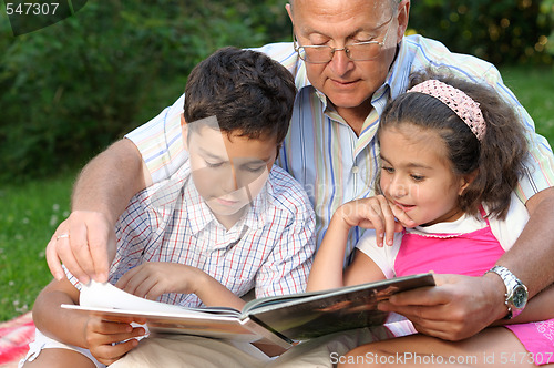 Image of Grandfather and kids reading book