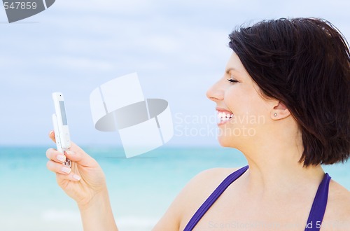 Image of happy woman with phone on the beach