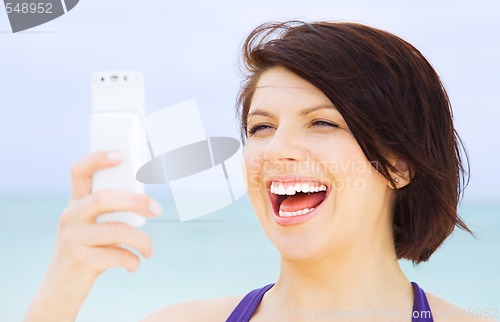 Image of happy woman with phone on the beach