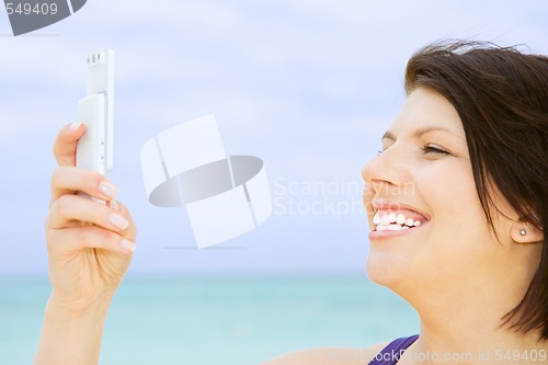 Image of happy woman with phone on the beach