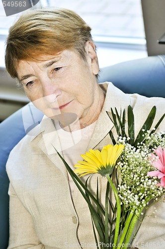 Image of Sad elderly woman with flowers