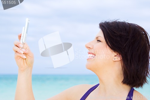 Image of happy woman with phone on the beach