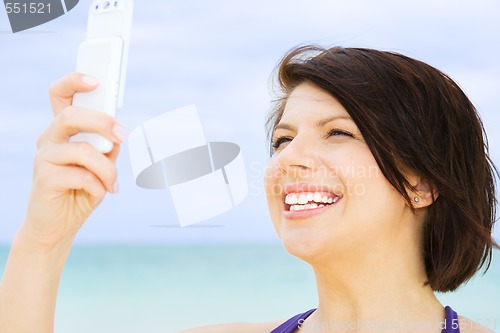 Image of happy woman with phone on the beach