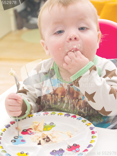 Image of Cute baby toddler on his first birthday eating cake