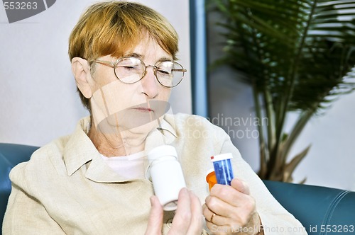 Image of Elderly woman reading pill bottles