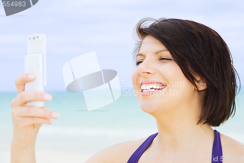 Image of happy woman with phone on the beach